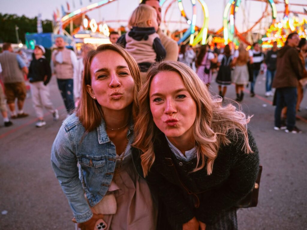 Two friends posing for the camera at a street fair