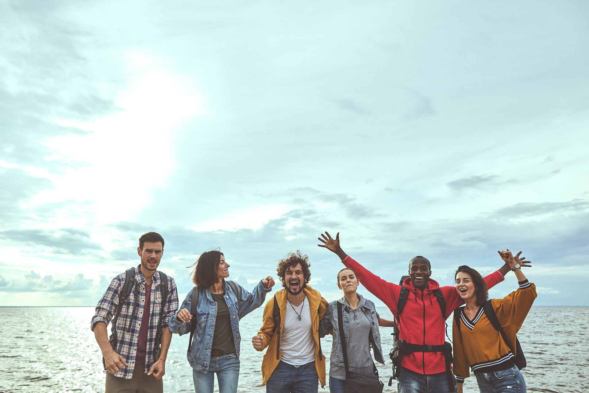 A group of friends outdoors and cheering in a group in front of the ocean